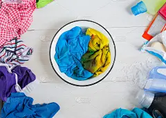 孩子们的脏衣服散落在一张白色的木桌上。搜索洗衣点信息的概念，洗衣点是清洗衣物的最佳方法。横幅宣传广告