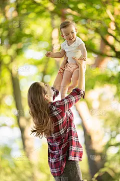 快乐的年轻妈妈在公园里吐了她的小女儿。