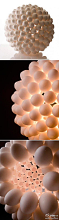 #光影空间#【蛋壳灯】这款蛋壳灯灯具的外壳非常具有震撼力，密密麻麻排列着许多圆球。不过蛋壳灯真正的创意点还不仅仅在造型上，更在于它的材料。这些密密麻麻排列的小球其实都是用鸡蛋壳制成的。 如果蛋壳灯用的是活鸡蛋，灯具的辐射温度又刚好，时间又足够， 好多小鸡出生了哦，